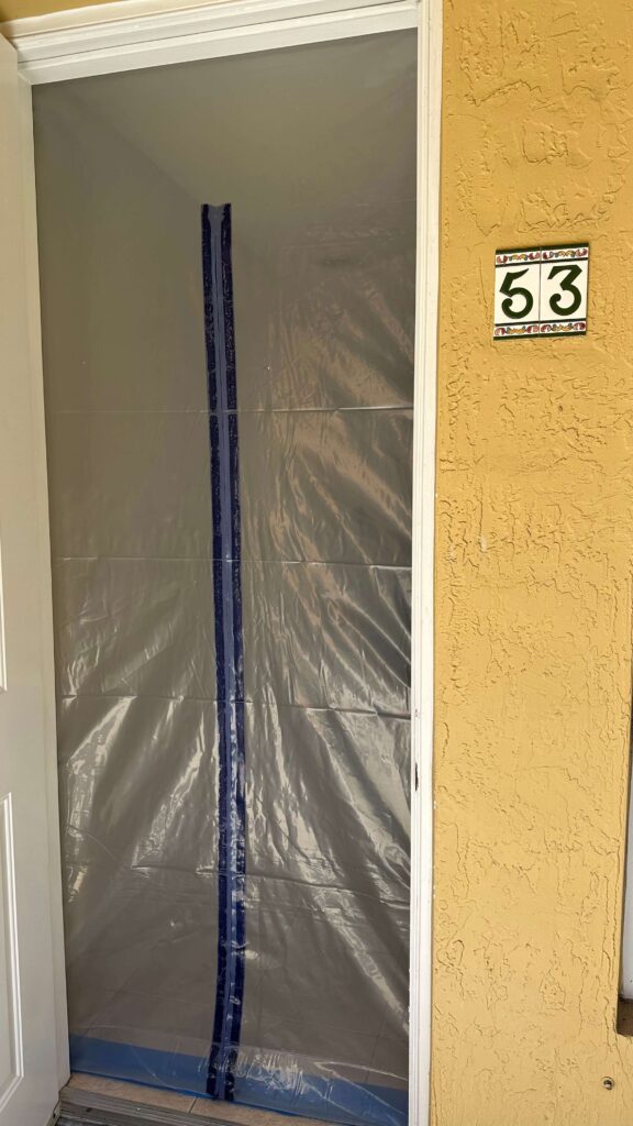 Professional Mold Remediation in West Palm Beach, FL 15 Door covered with plastic sheeting, indicating mold cleaning in progress at the entrance of a house.