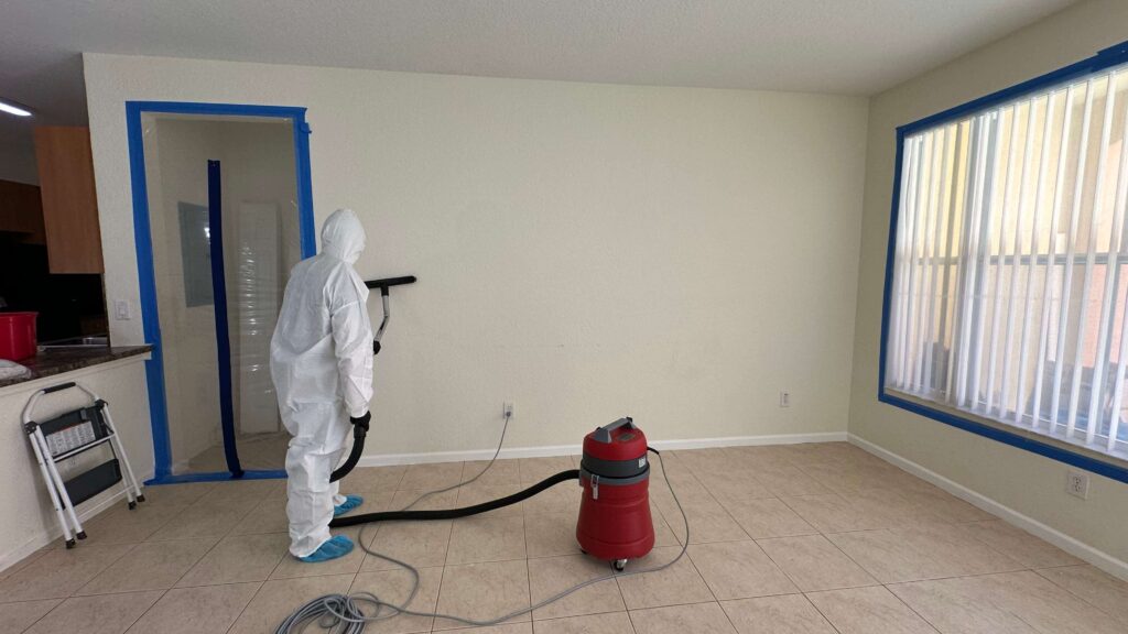 Professional Mold Remediation in West Palm Beach, FL 1 A man in a white suit is painting a room while addressing mold cleaning on the walls.