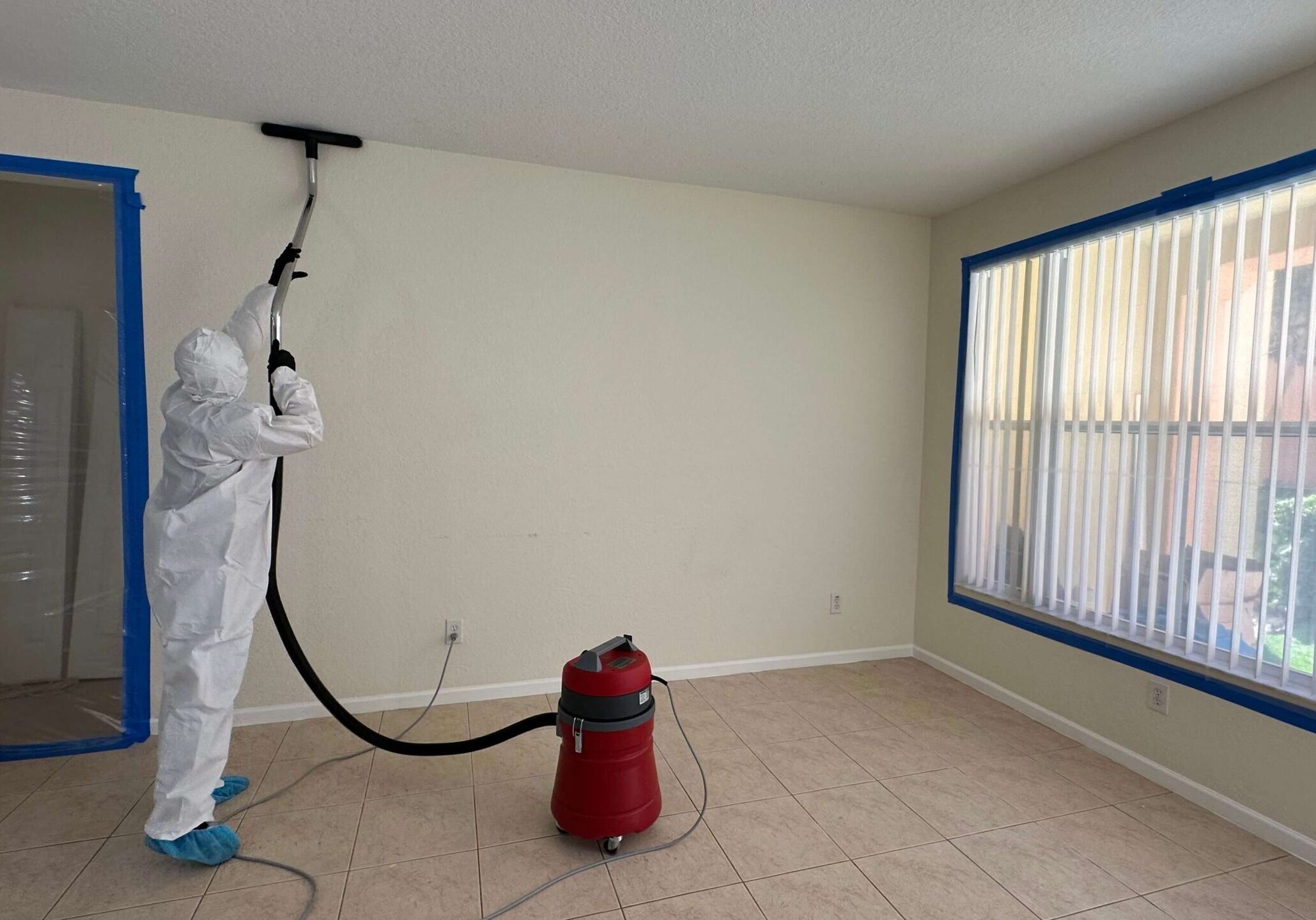 man-in-suit-cleaning-mold A person in a white suit is painting a room after mold cleaning, ensuring a fresh and safe environment.